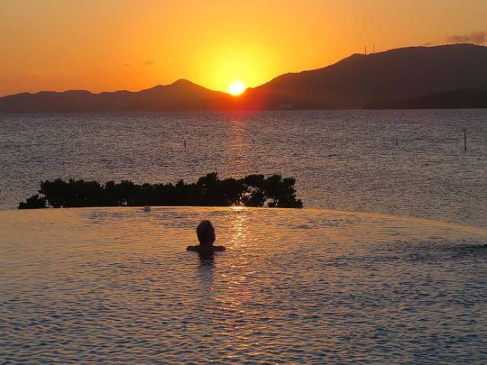 guest in the infinity pool watching the sunset